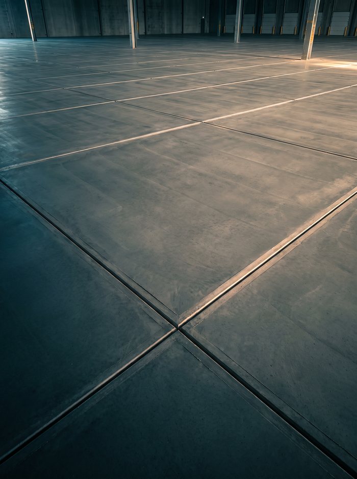 Illustration: long saw-cut control joints across a warehouse floor